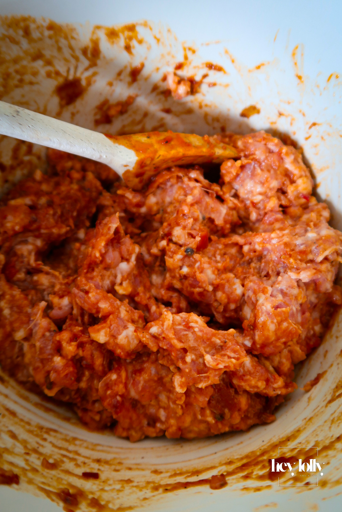 Close-up of seasoned sausage meat with flecks of pepper and dried oregano.