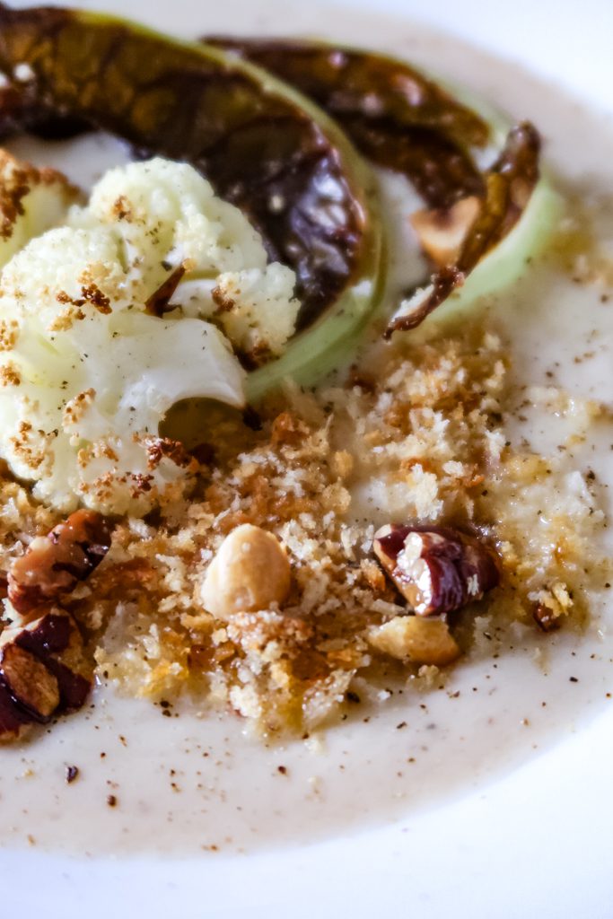 Close up of creamy cauliflower and white bean soup on a spoon showing smooth texture