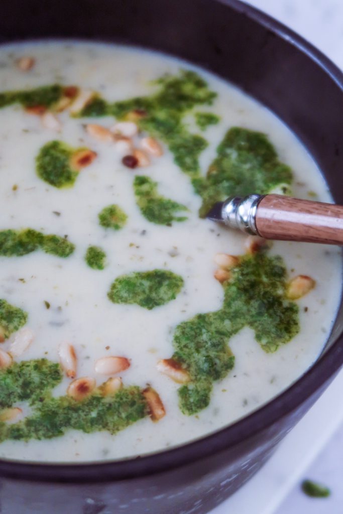 Close-up of creamy white bean and orzo soup showing soft beans and kale pesto
