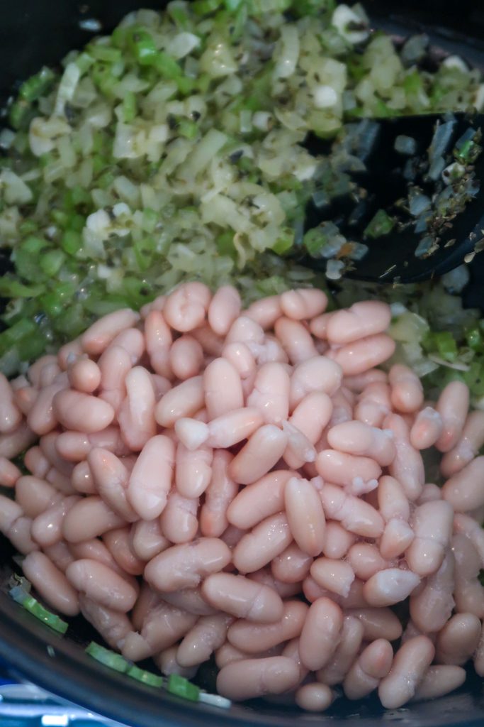 Aromatics sweating slowly in olive oil: onion, celery and garlic with white beans