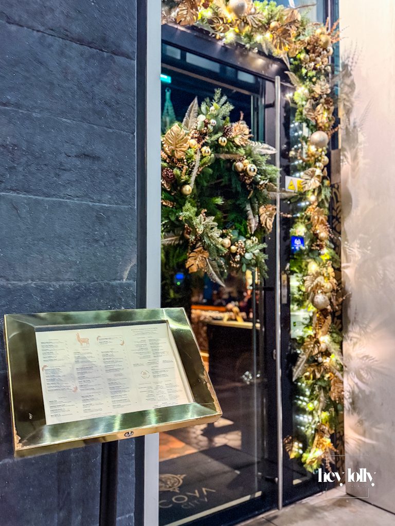 Exterior of COYA City London at night, glowing entrance in the City of London