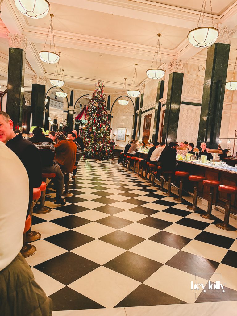 Central lobby of The Ned London with marble floors and festive décor