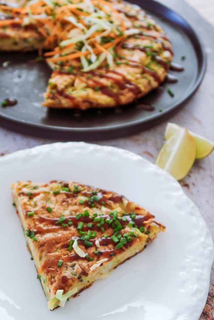 close-up of okonomiyaki pancake with gochujang showing crisp edges, cabbage interior and sauce drizzles