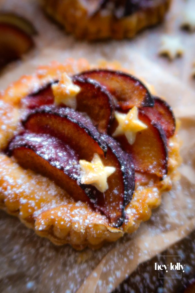 Freshly baked plum and vanilla custard tarts with puffed pastry and soft fruit