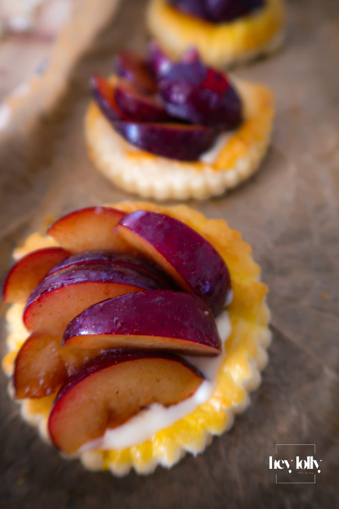 Arranging sliced plums over custard on puff pastry tarts