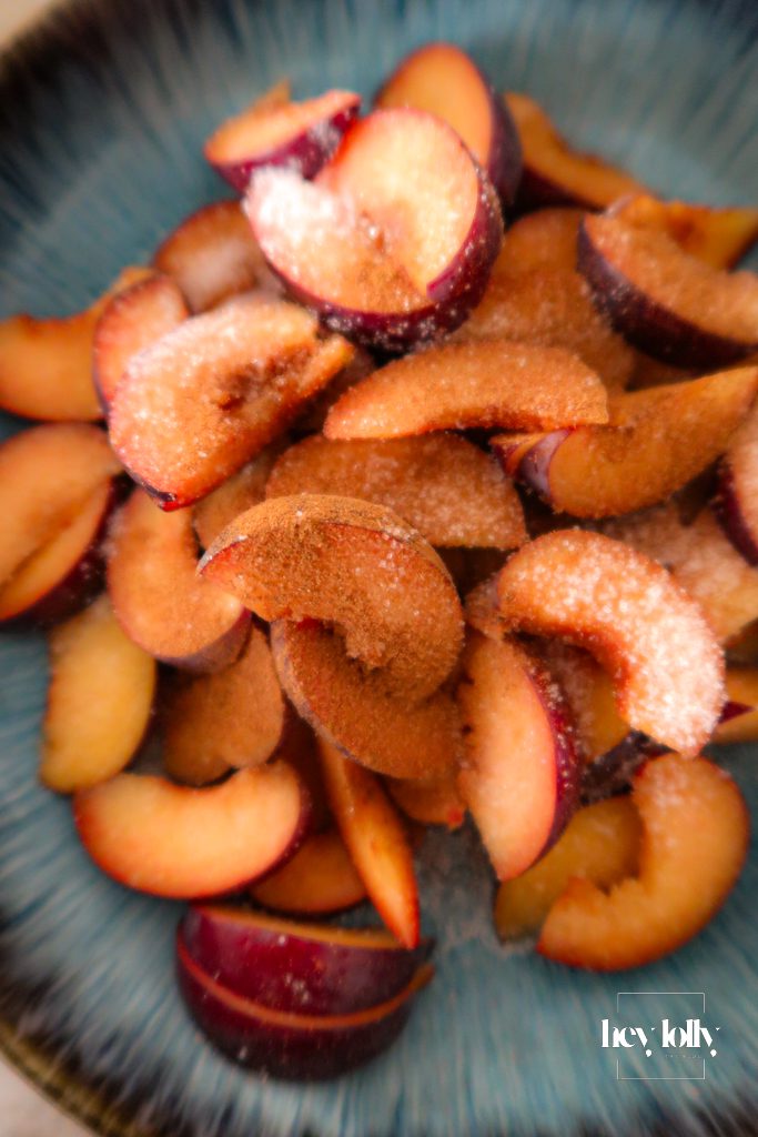 Close-up of plums sprinkled with cinnamon and sugar before baking