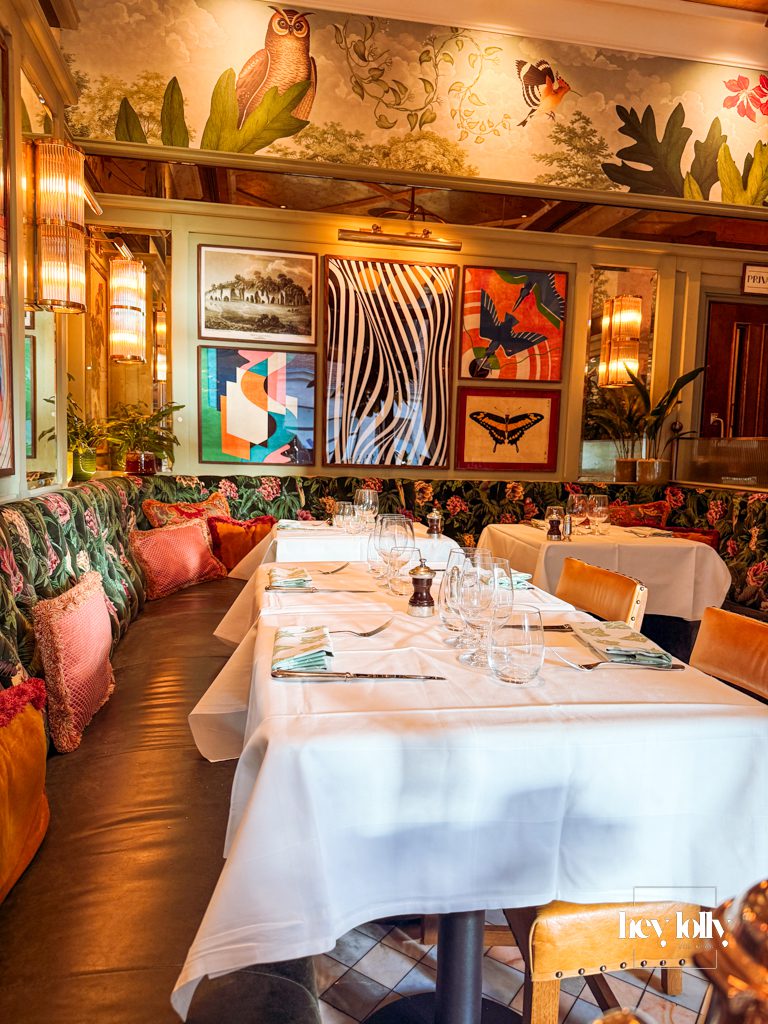 Interior of The Ivy Nottingham dining room with brass tables, velvet seating and artwork creating an elegant restaurant setting