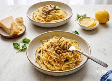 Preserved lemon pasta with roasted walnut pesto, basil and grated parmesan in a ceramic bowl