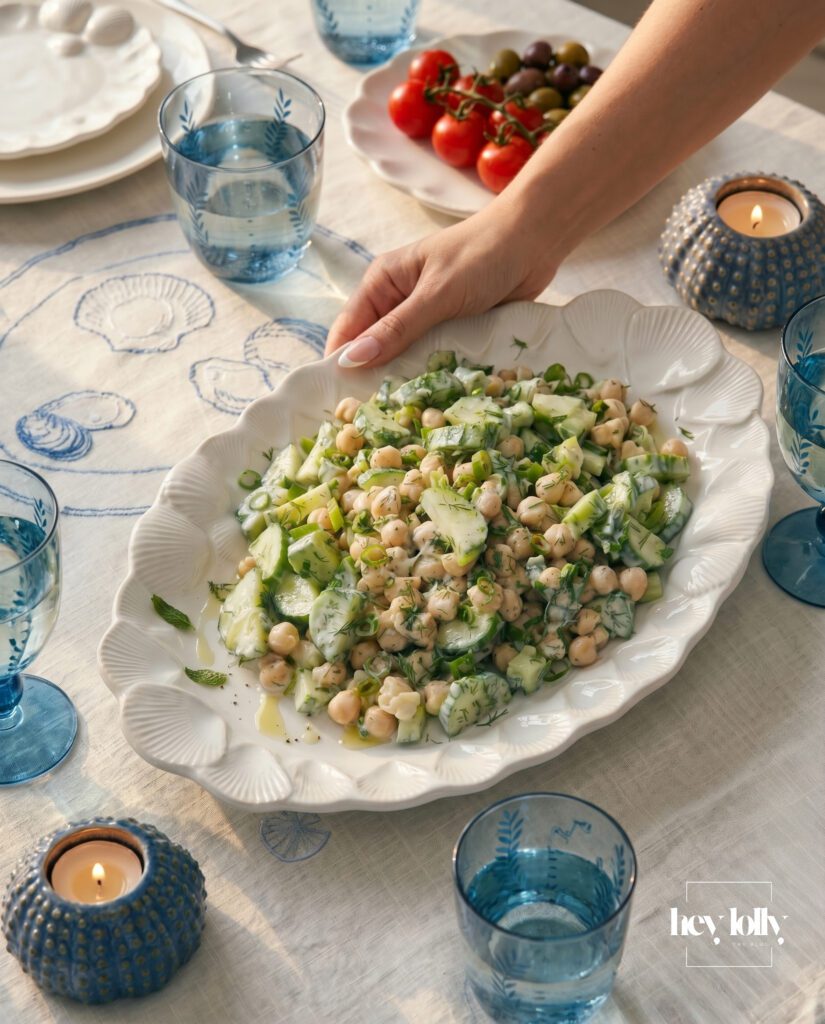 Tzatziki chickpea salad on a shell platter with Mediterranean table setting and blue coastal styling